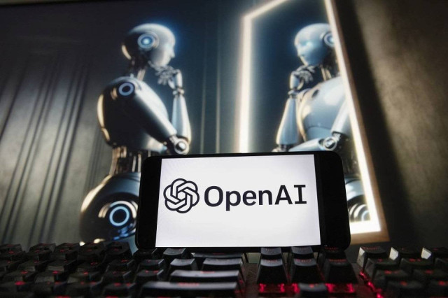 The OpenAI logo is displayed on a cell phone with an image on a computer monitor generated by ChatGPT's Dall-E text-to-image model, Dec. 8, 2023, in Boston.